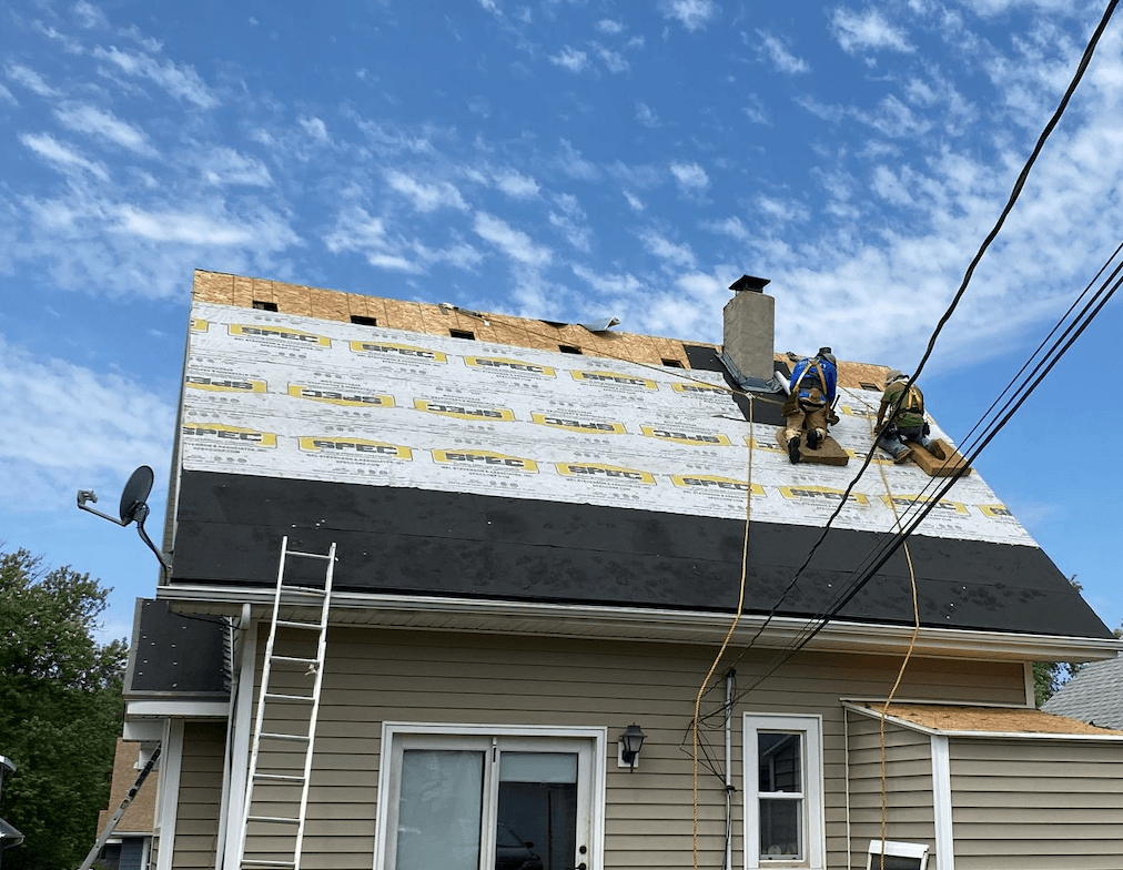 Royalty Roofing crew installing new underlayment around a brick chimney on an Omaha home before flashing and shingles go on