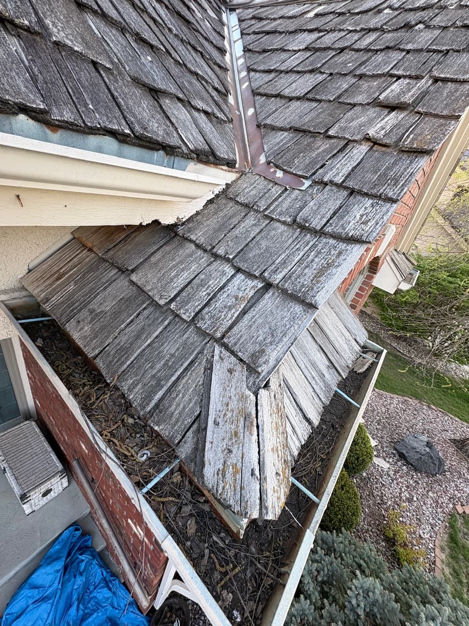Weathered cedar shake roof in Omaha with rusted metal valley flashing between roof planes