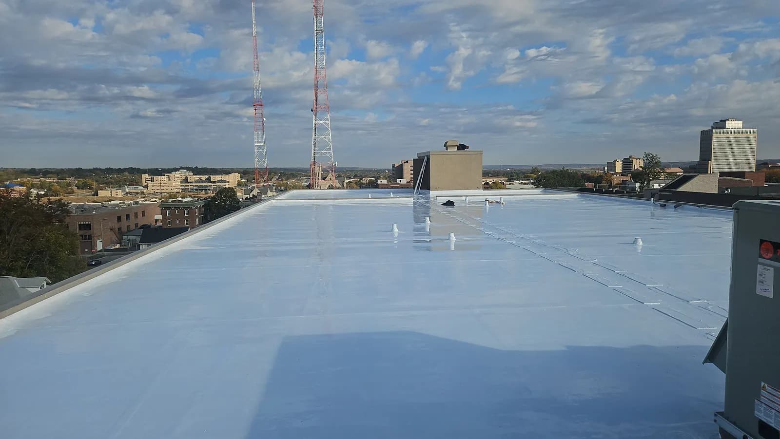 Freshly coated white flat roof on a downtown commercial building with radio towers in the background