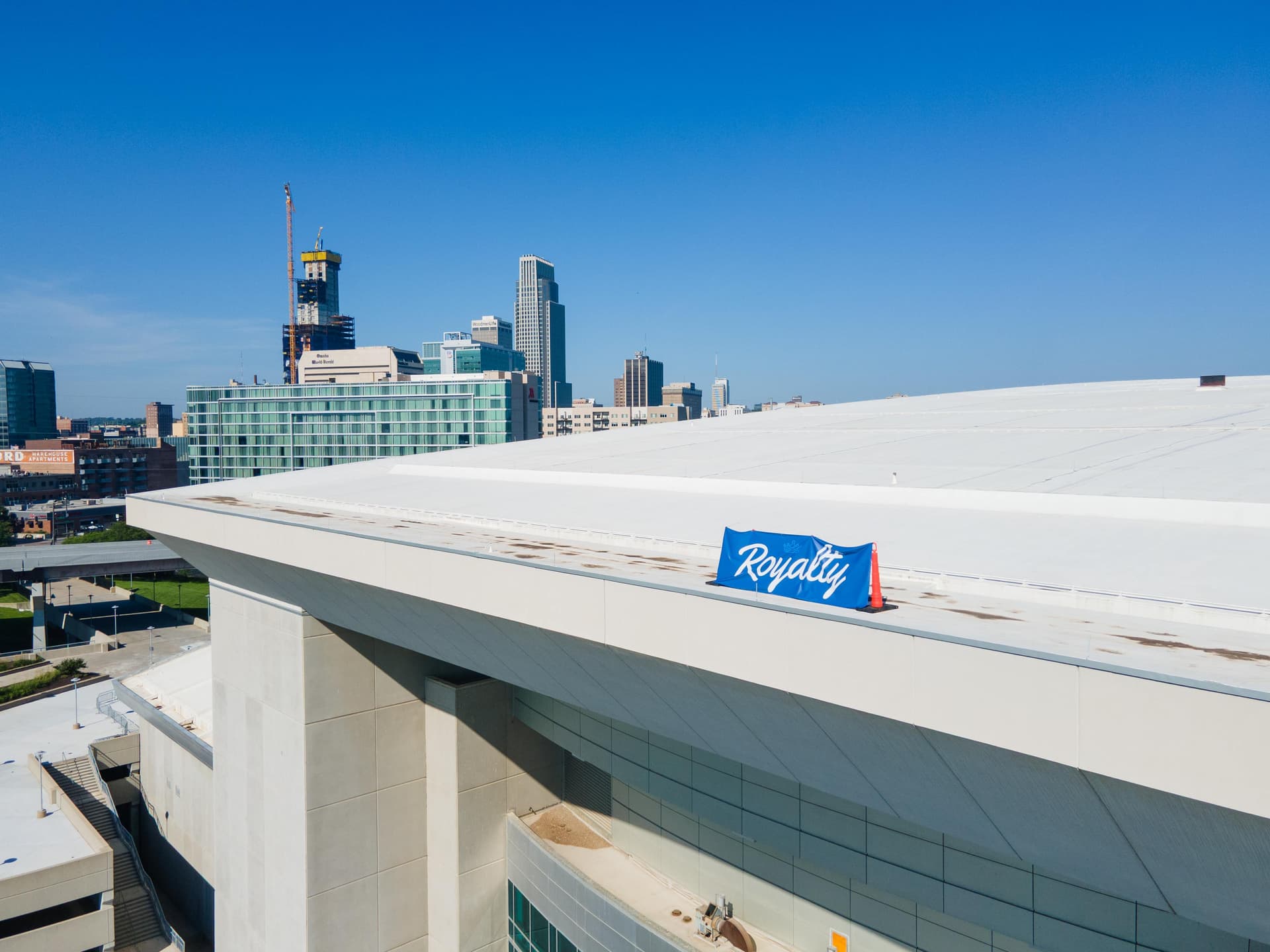 Aerial view of a commercial roof with a Royalty banner and the downtown Omaha skyline