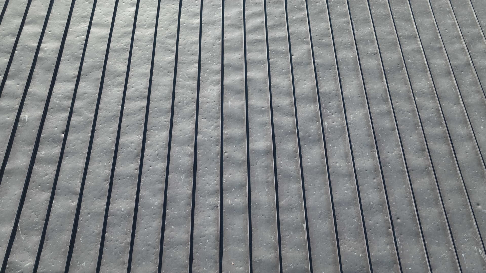 Aerial view of a standing seam metal roof covered in hail dents