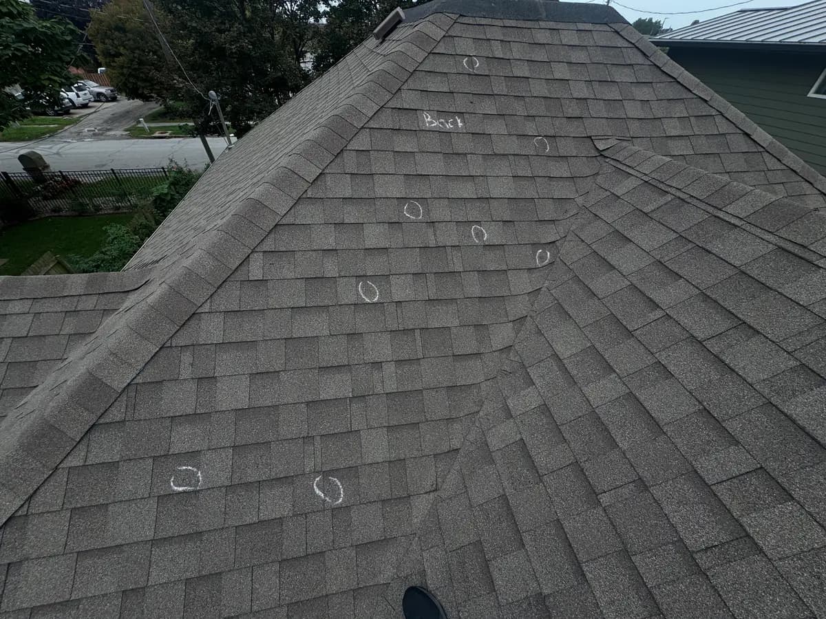 Gray architectural shingle roof with white chalk circles marking individual hail strikes found during a Royalty Roofing inspection