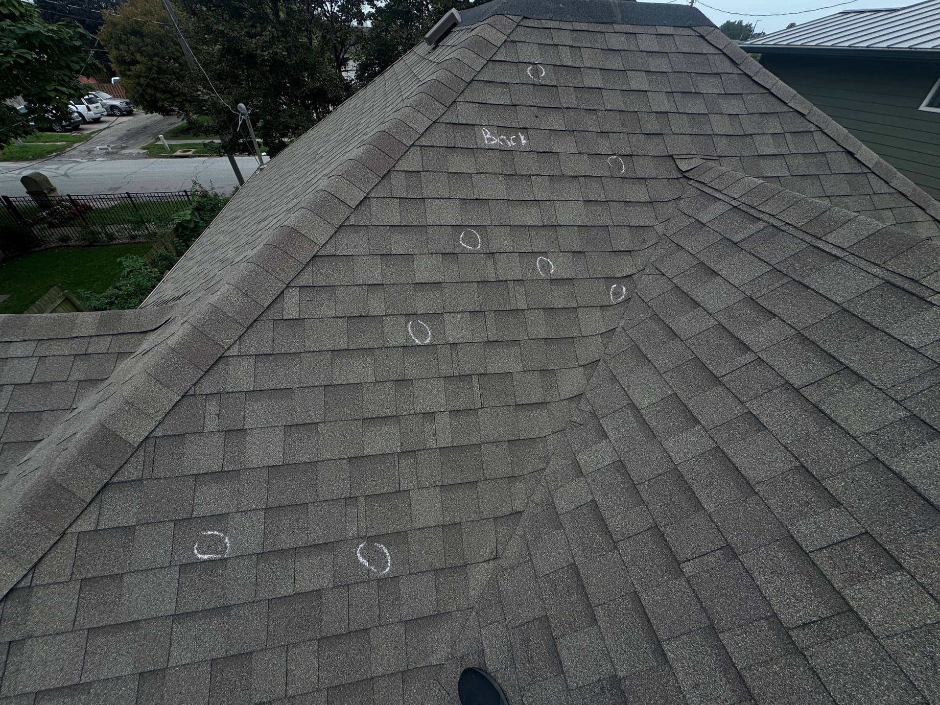 Hail hits circled in chalk on architectural shingles during a Royalty Roofing hail inspection in Millard