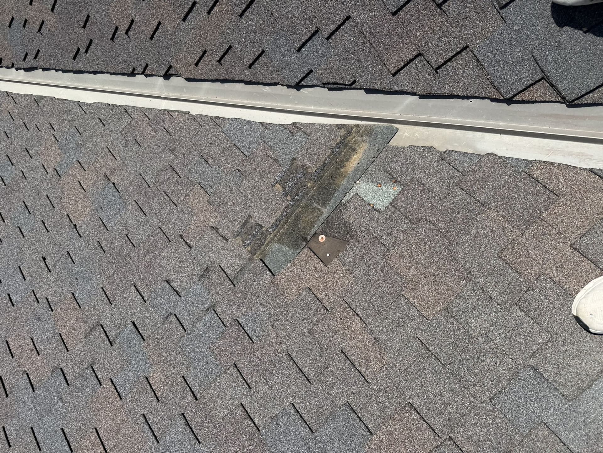Missing shingle tabs exposing the underlayment next to a metal valley on an Elkhorn roof