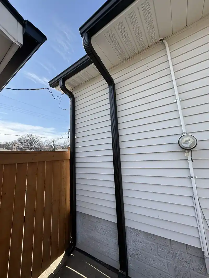 Black gutters and downspout against white siding and trim