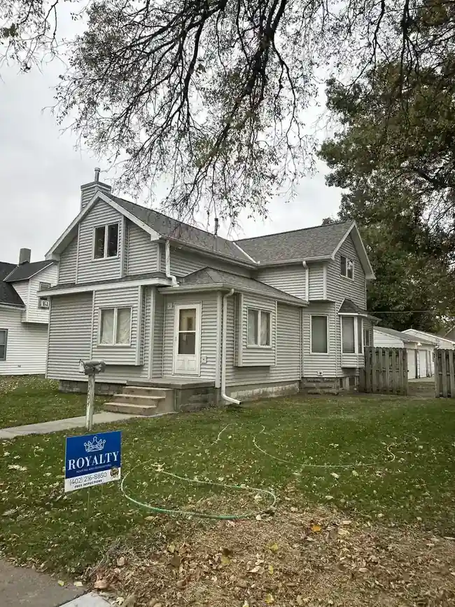 Completed Royalty Roofing and Siding project on a gray Victorian home with yard sign