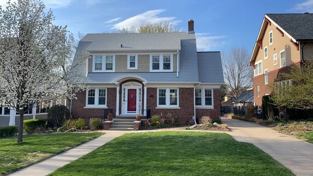 Shake-style siding on the gable of a brick Dutch Colonial home in Midtown Omaha
