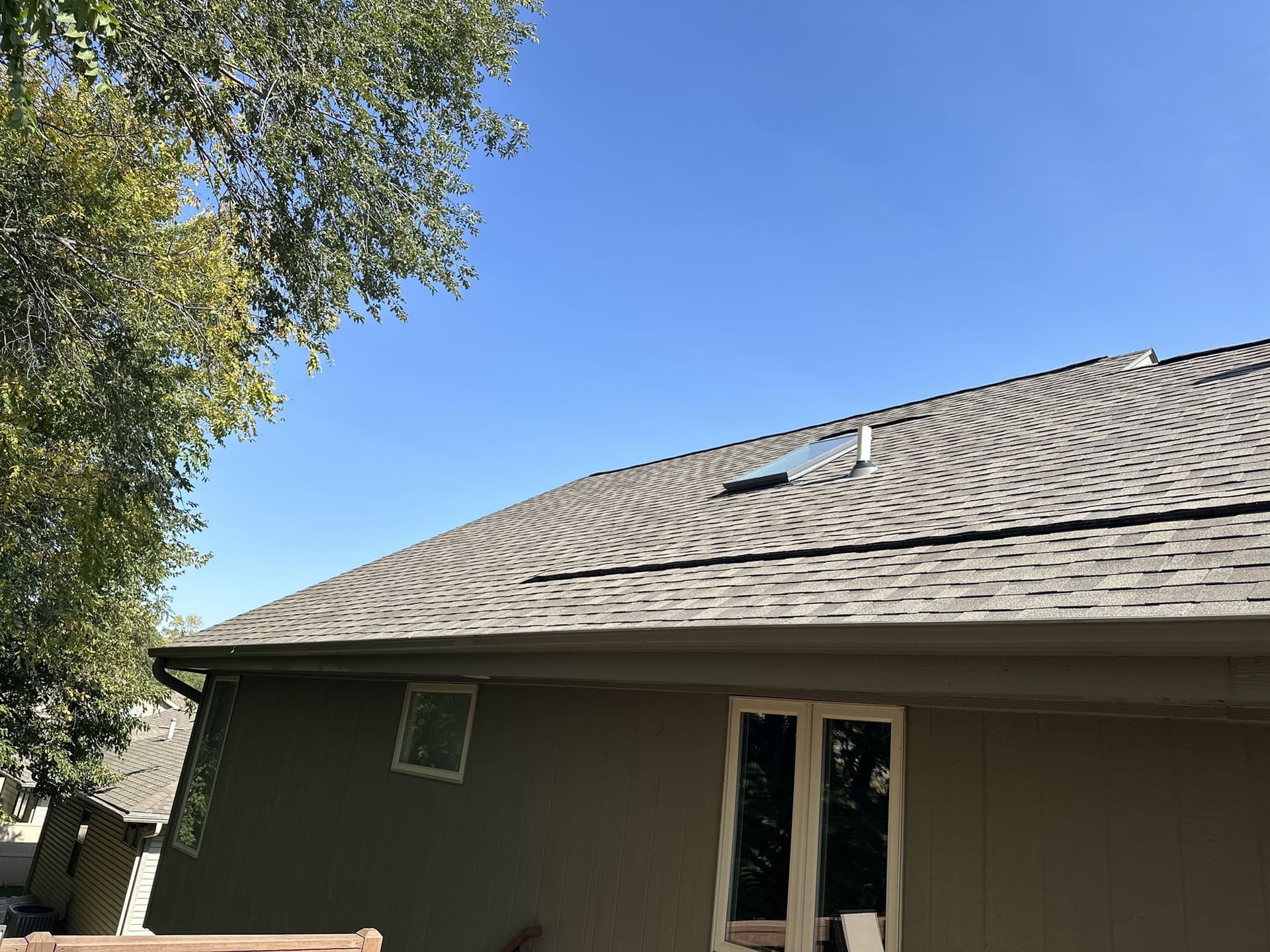 Skylight properly integrated into a shingle roof with clean, continuous flashing woven into the surrounding shingles on an Omaha home